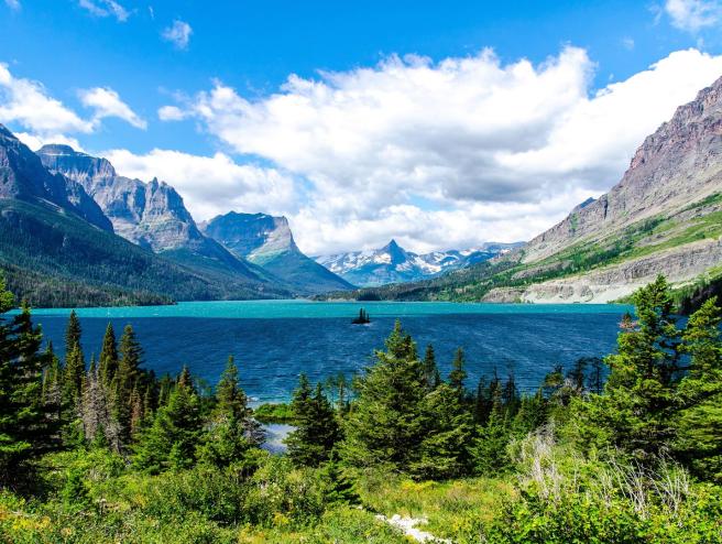 a mountain lake with a blue sky and evergreen trees